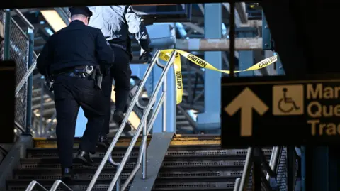 Getty Images Police investigate at the Coney Island-Stillwell Avenue Station in Brooklyn after a woman aboard a subway car was set on fire and died. A police officer can be seen walking up a stairwell with some yellow police tape flickering in the distance
