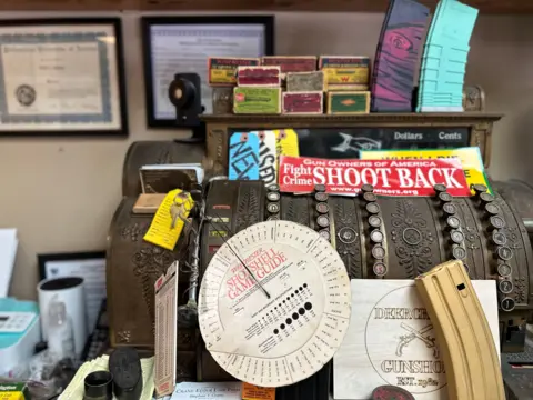 A vintage cash register is adorned with a sign that reads "fight crime, shoot back"