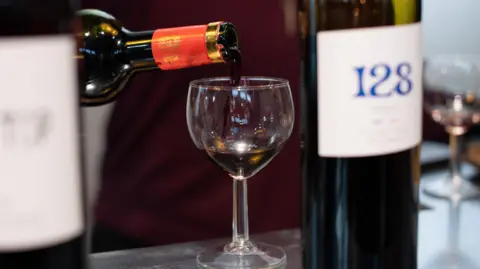 Someone pours a glass of non-alcoholic wine